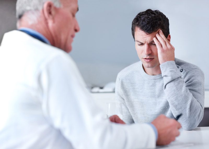 Male-patient-describing-headache-to-doctor